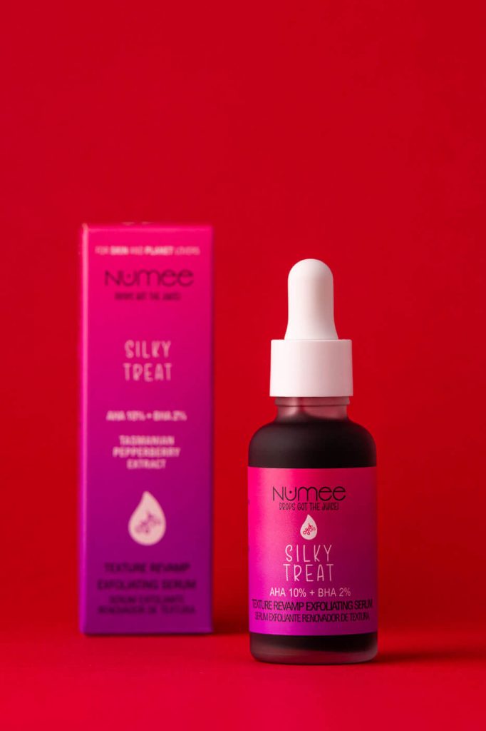 una caja desenfocada de serum y el bote enfocado al lado juntos en un fondo rojo