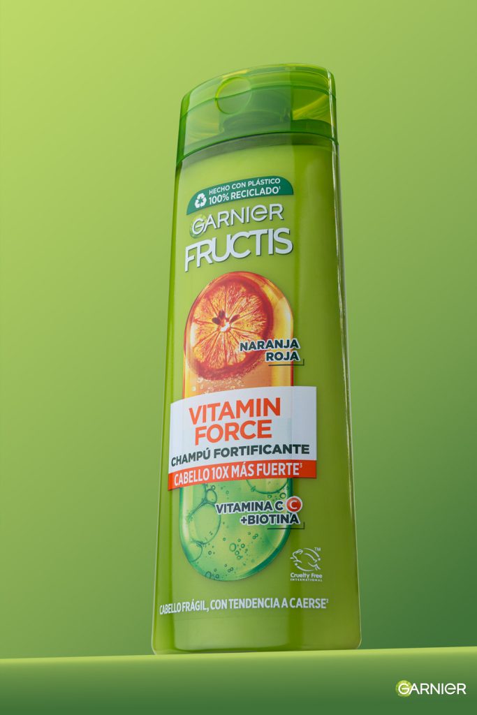 Fotografía de producto champú Garnier Fructis Vitamin Force sobre fondo verde lima en estudio Sevilla