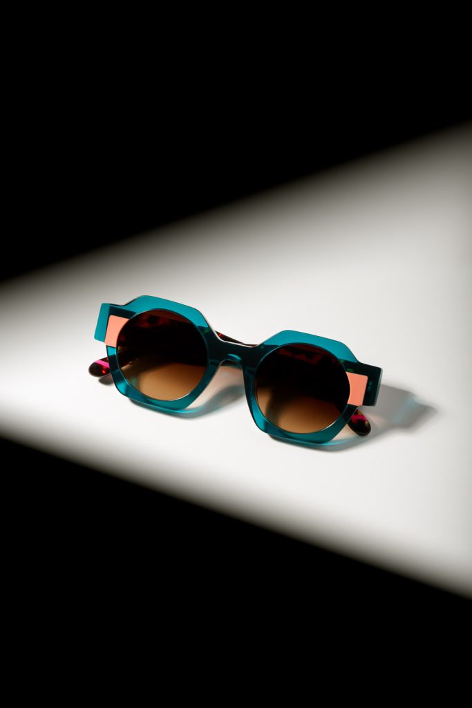 Fotografía de producto gafas de sol redondas bicolor con luz dramática sobre superficie blanca en estudio Sevilla